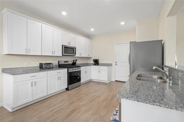 a kitchen with granite countertop white cabinets and stainless steel appliances