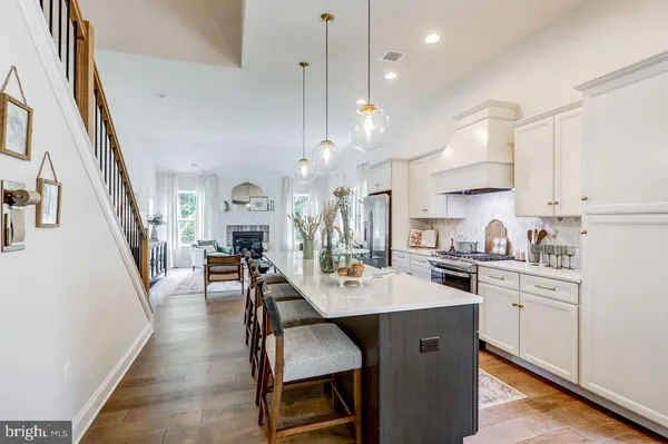 a kitchen that has a lot of cabinets a sink a stove and chairs in it