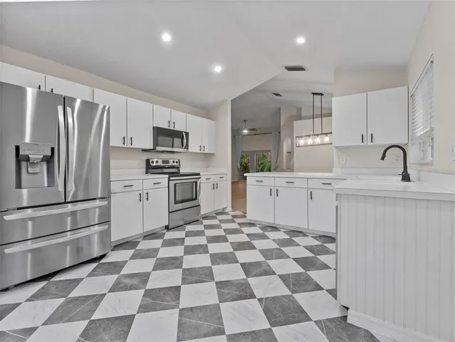 a kitchen with a sink a refrigerator and white cabinets