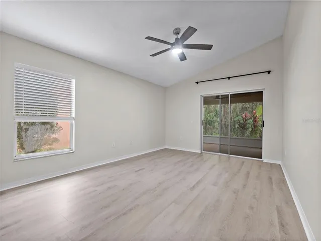 an empty room with wooden floor fan and windows