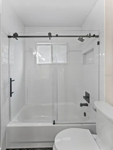 a bathroom with a shower a toilet and a bathtub