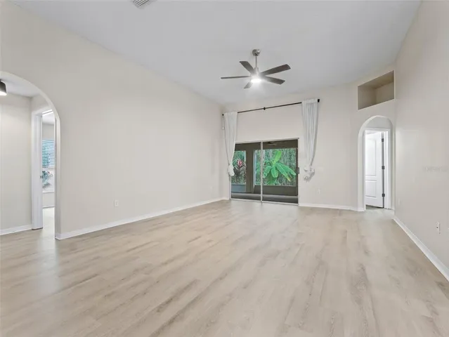 a view of an empty room with a window and wooden floor