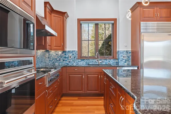 a kitchen with stainless steel appliances granite countertop a sink and a wooden cabinets