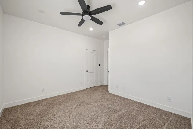 an empty room with a ceiling fan and carpet