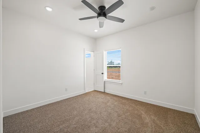 an empty room with a ceiling fan and a window