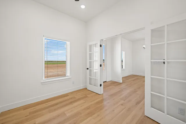 an empty room with wooden floor and windows