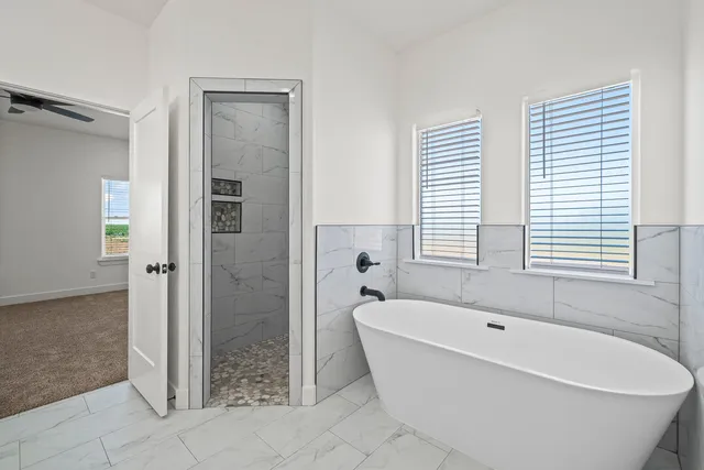 a white bath tub sitting in a bathroom next to a window