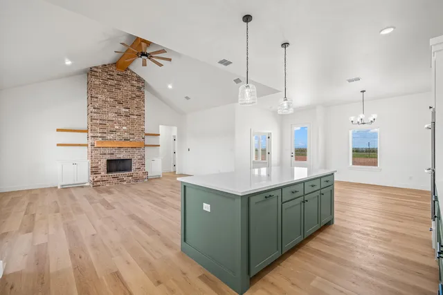 a view of a kitchen with kitchen island a sink wooden floor and a large window
