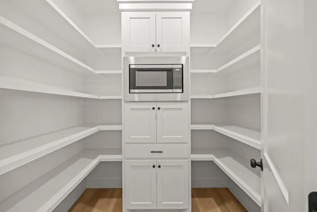 a view of an empty room with wooden floor and cabinet