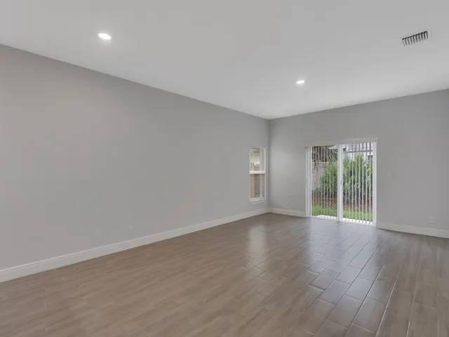 a view of an empty room with wooden floor and windows