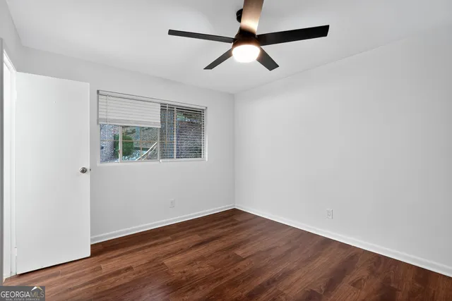 an empty room with wooden floor fan and windows