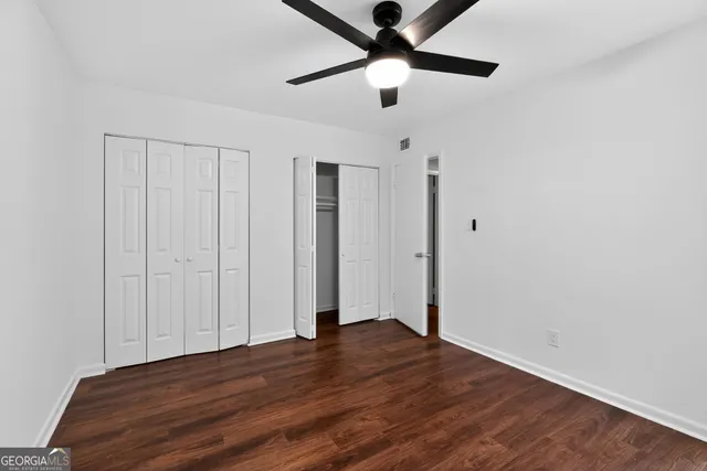 an empty room with wooden floor closet and ceiling fan