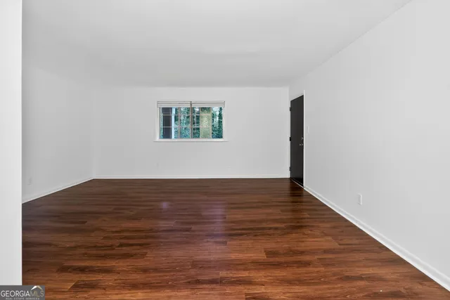 a view of an empty room with wooden floor and closet