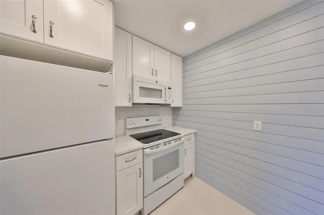 a kitchen with white cabinets and white appliances