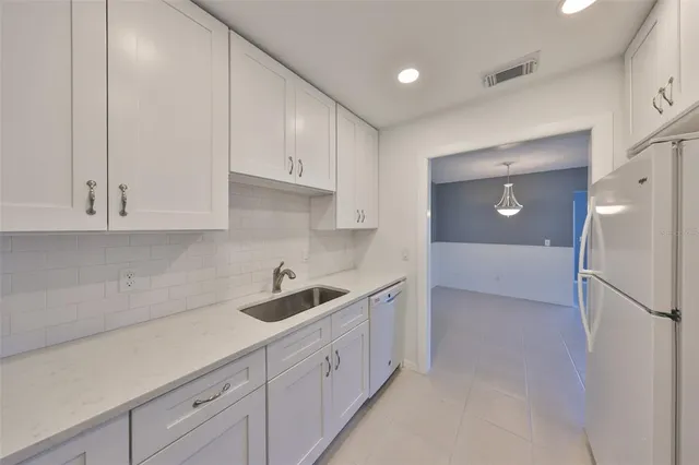 a kitchen with white cabinets and refrigerator