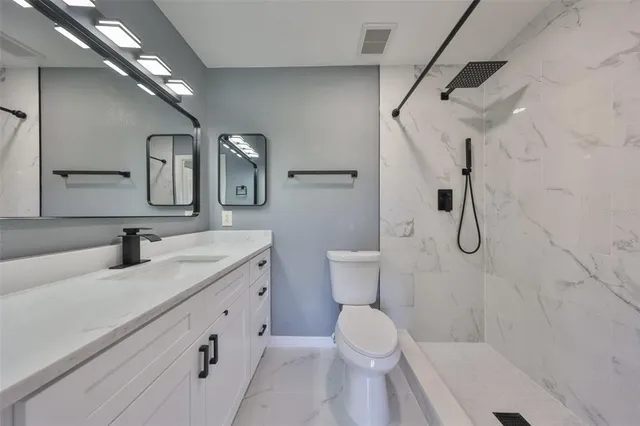 a bathroom with a granite countertop sink a toilet and shower