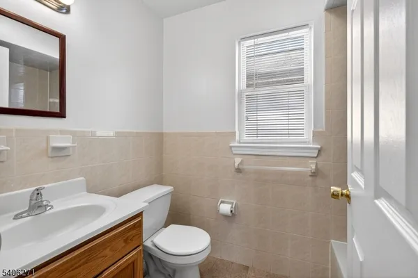 a bathroom with a toilet a sink a mirror and a window
