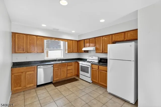 a kitchen with granite countertop stainless steel appliances a refrigerator sink and cabinets
