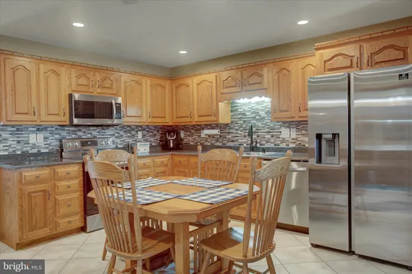 a kitchen with stainless steel appliances granite countertop a refrigerator a stove a sink a dining table and chairs