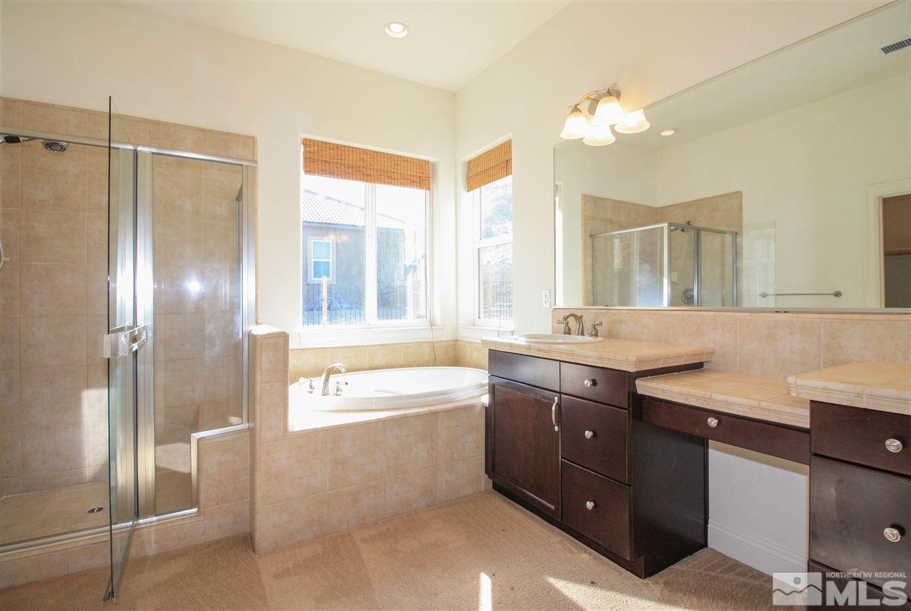 7505 Rough Rock Drive Reno, NV 89502 - Photo 20 of 25 a bathroom with a granite countertop bathtub a sink and a mirror