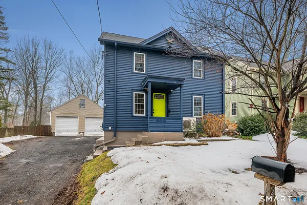 a front view of a house with a yard outdoor seating and covered with trees