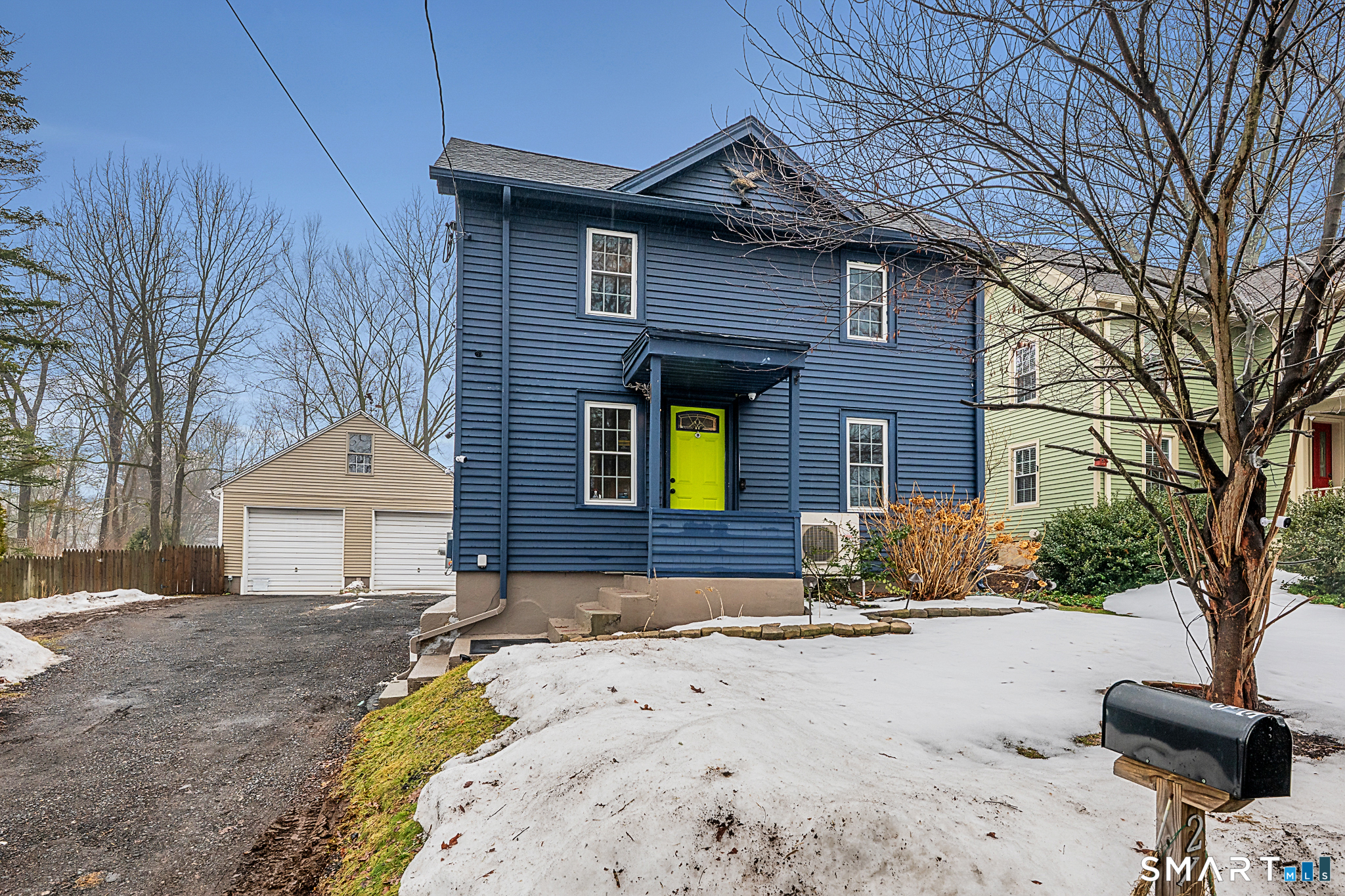 a front view of a house with a yard outdoor seating and covered with trees