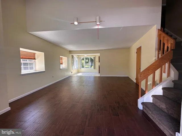 a view of an empty room with wooden floor and a flat screen tv