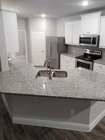 a kitchen with stainless steel appliances granite countertop a sink a stove and a granite counter top