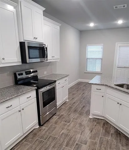 a kitchen with stainless steel appliances granite countertop a sink a stove a microwave and wooden cabinets