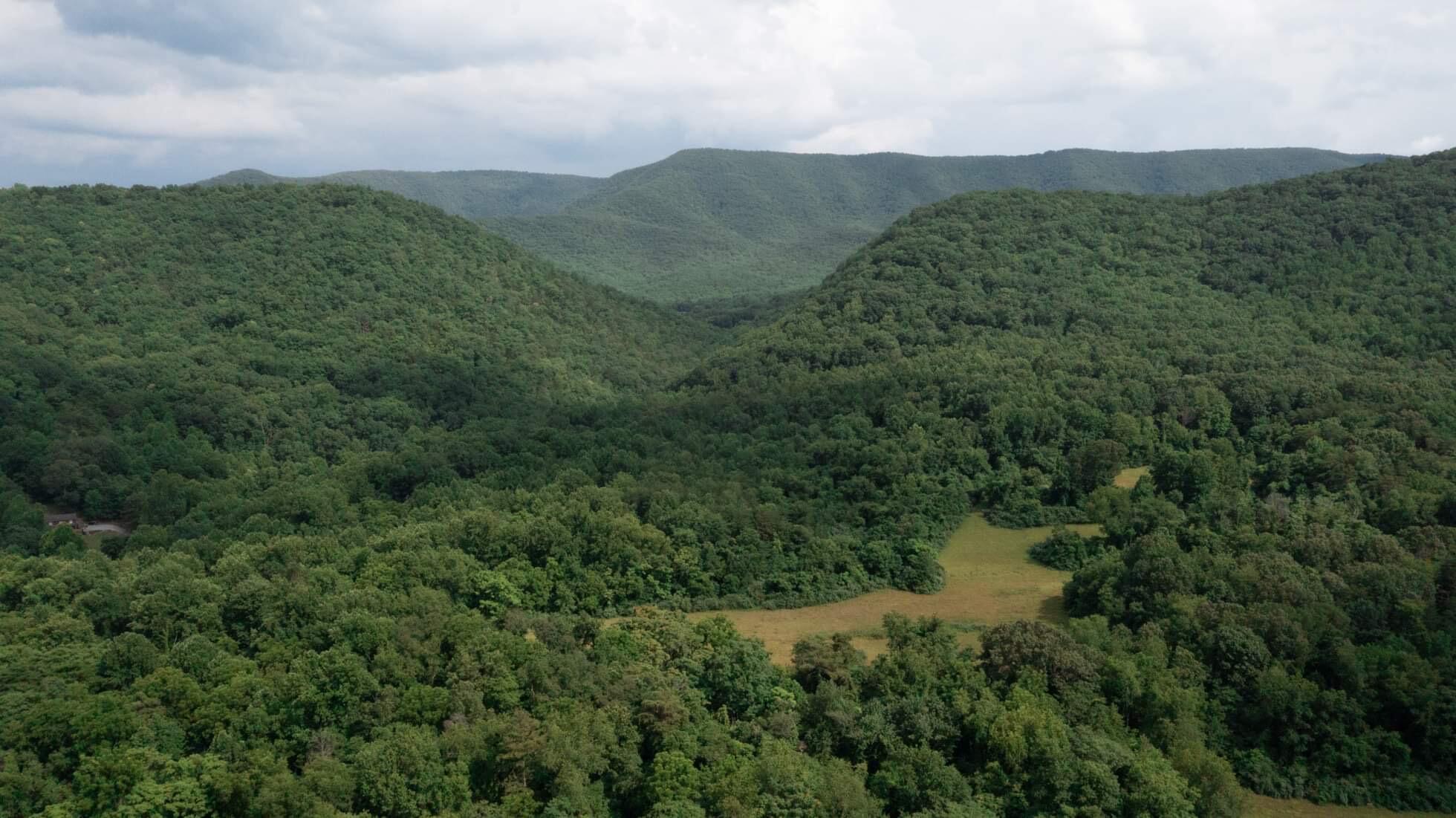 an aerial view of a city with lots of residential buildings green landscape and mountain view