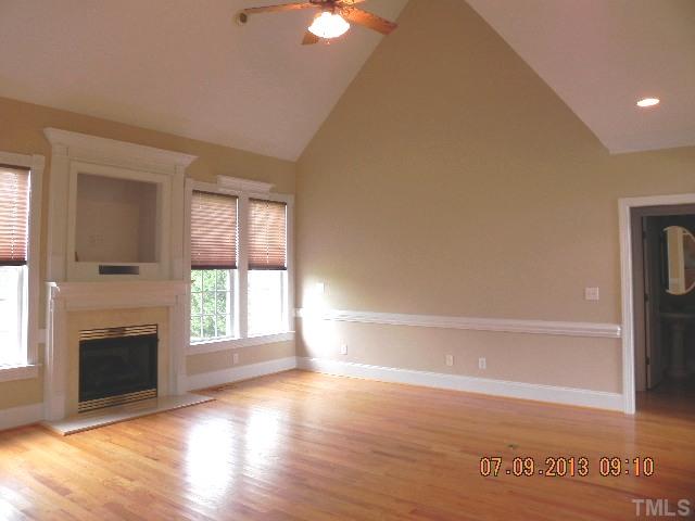 213 Waterville Street Raleigh, NC 27603 - Photo 5 of 24 an empty room with wooden floor a fireplace and windows