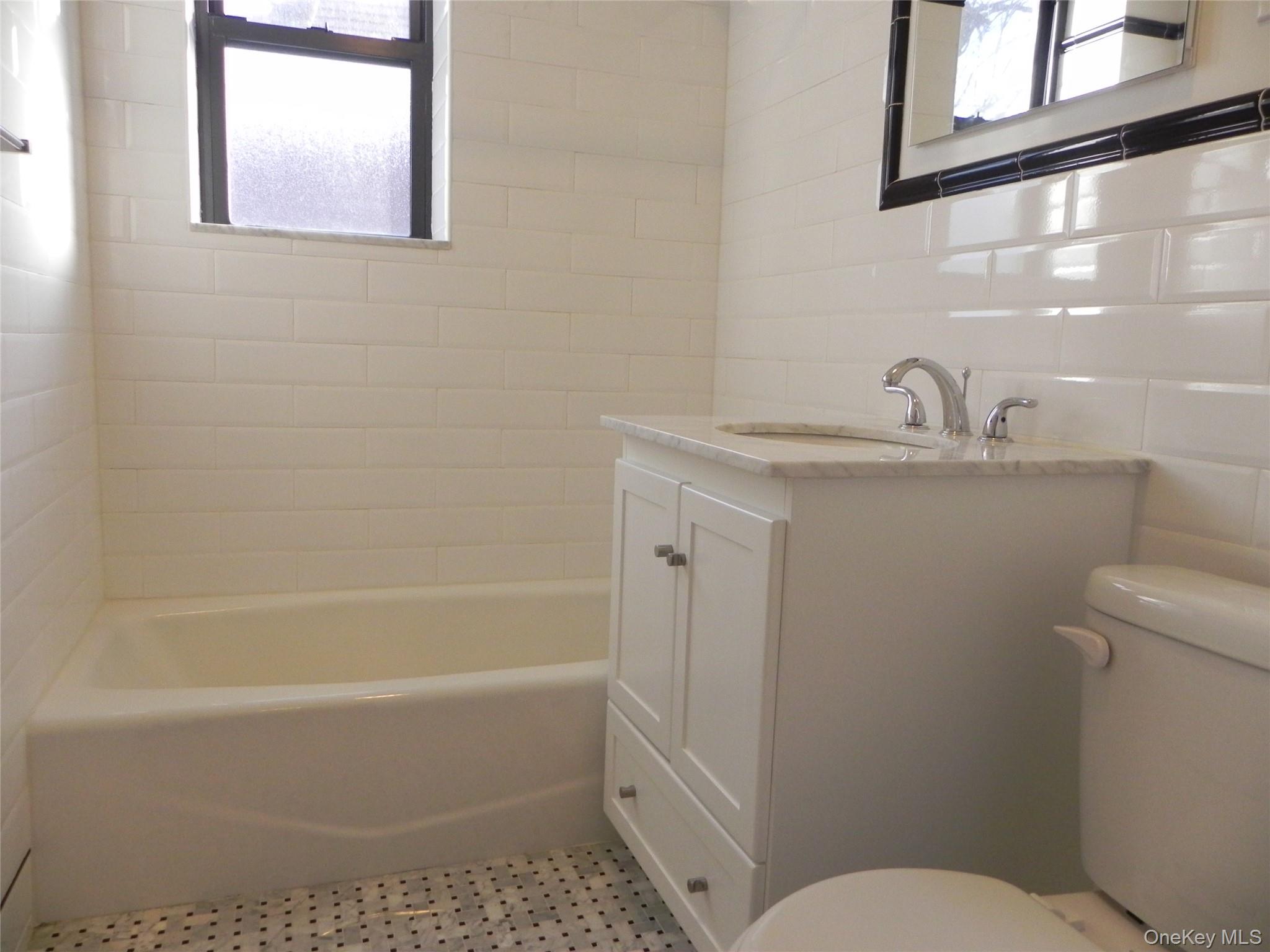 160 South Middle Neck Road, Unit 1N Great Neck, NY 11021 - Photo 15 of 15 Full bathroom featuring tiled shower / bath, tile walls, decorative backsplash, vanity, and toilet