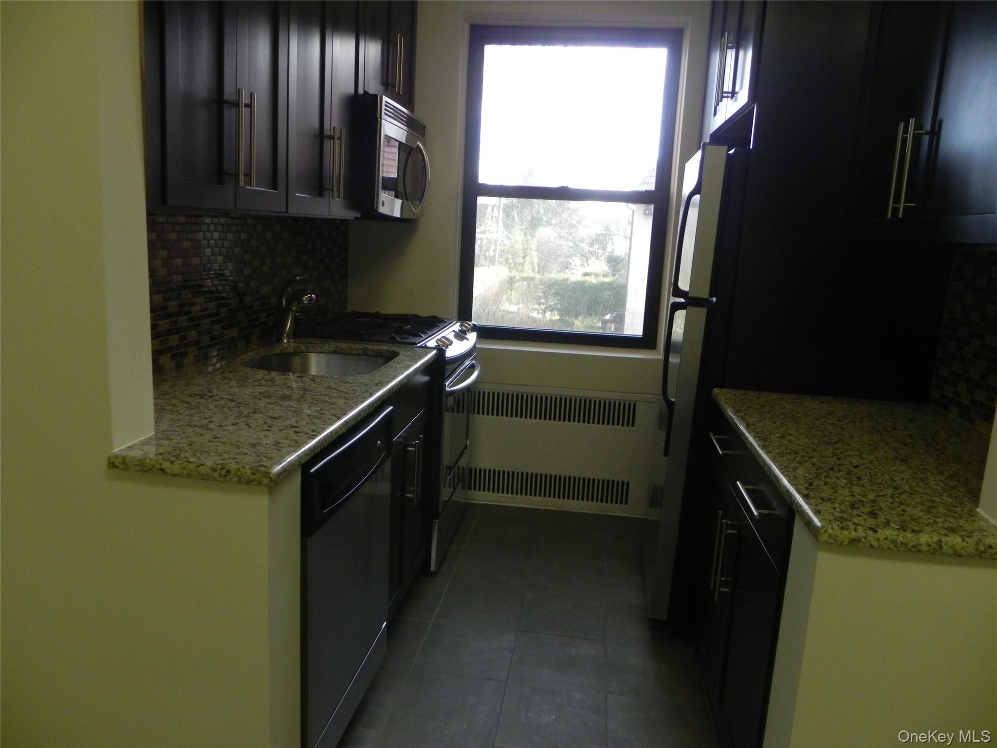 160 South Middle Neck Road, Unit 1N Great Neck, NY 11021 - Photo 7 of 15 Kitchen with light stone counters, appliances with stainless steel finishes, tile backsplash