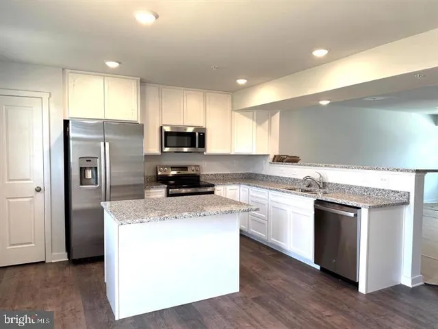a kitchen with a sink a microwave a refrigerator and white cabinets