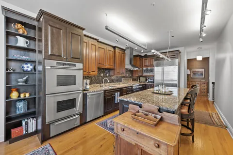 a kitchen with kitchen island a stove a refrigerator and a dining table with wooden floor