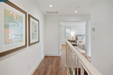a view of a hallway to a livingroom with wooden floor and furniture