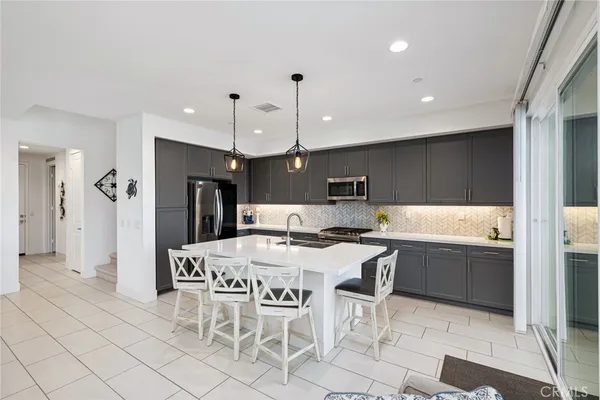 a kitchen with stainless steel appliances a table chairs and a view of living room