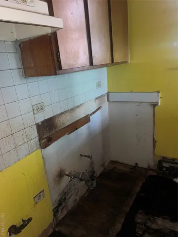a room with water heater and wooden cabinets