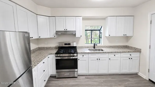 a kitchen with granite countertop white cabinets and white appliances