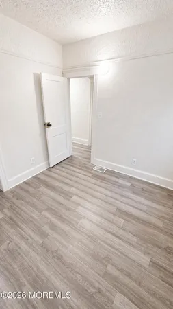 an empty room with wooden floor and white wall