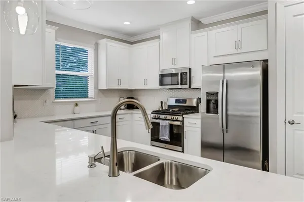 a kitchen with a refrigerator sink and white cabinets
