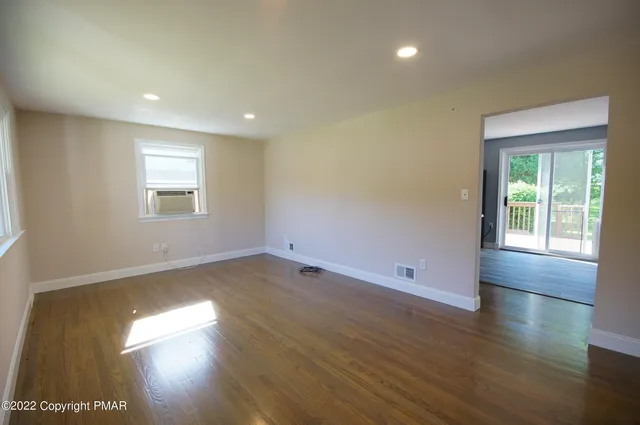 an empty room with wooden floor and windows
