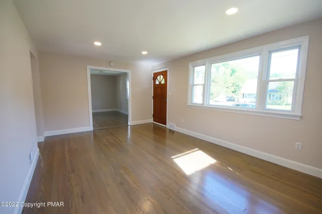 an empty room with wooden floor and windows