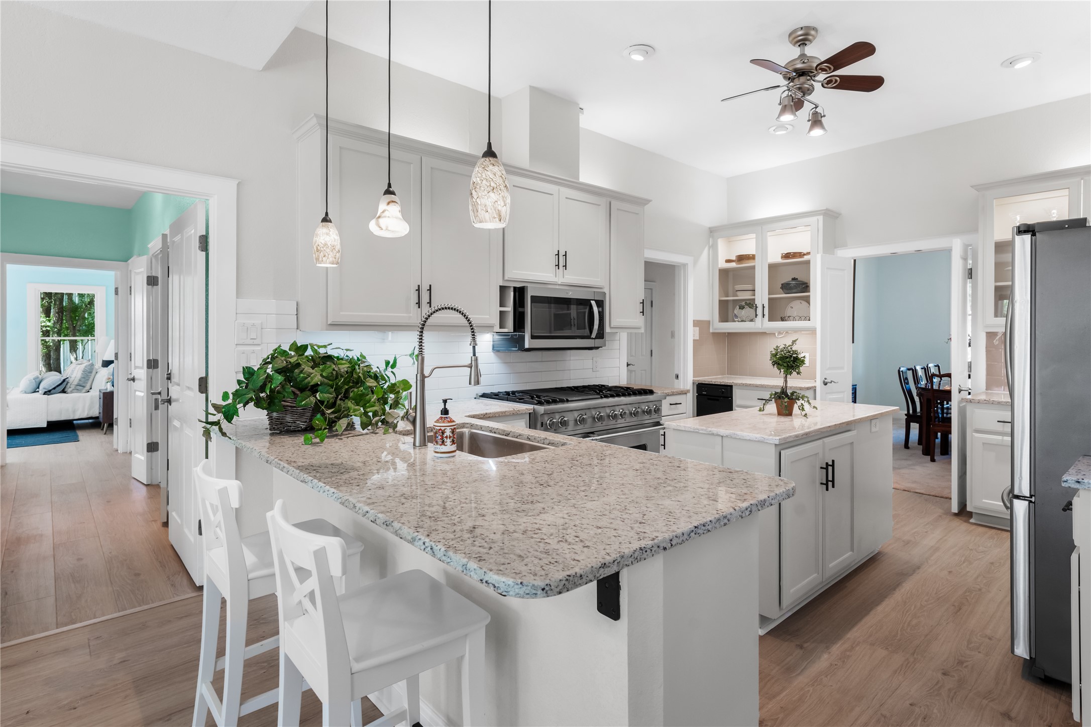 7670 Nez Perce Trace Manor, TX 78653 - Photo 8 of 40 Kitchen with a sink, light wood-type flooring, appliances with stainless steel finishes, a ceiling fan, and a peninsula