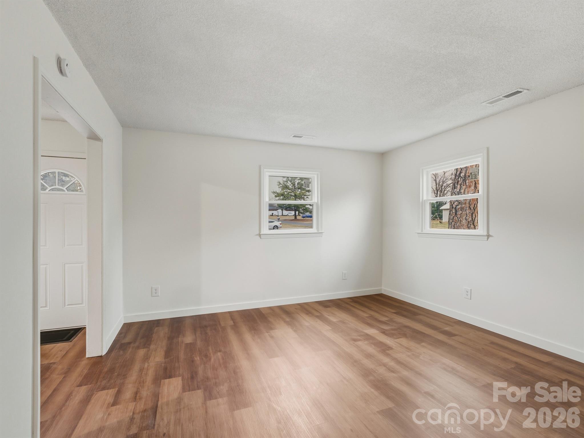 307 Jones Street Monroe, NC 28110 - Photo 8 of 22 an empty room with wooden floor and windows