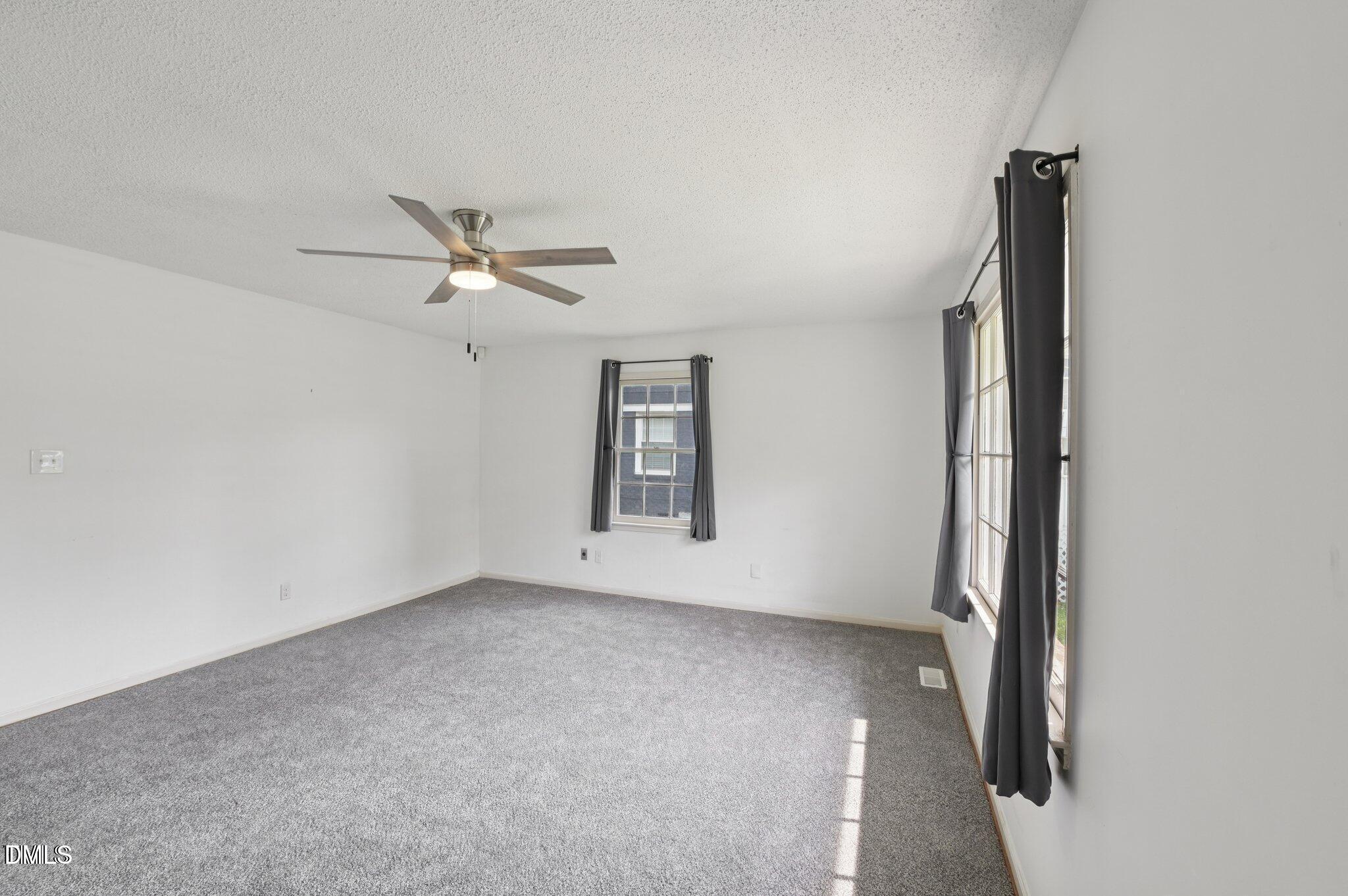 555 Dacian Road Raleigh, NC 27610 - Photo 6 of 16 an empty room with windows and ceiling fan