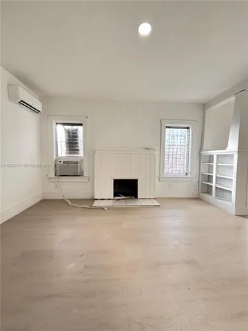 an empty room with a fireplace and windows