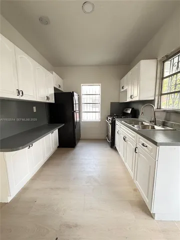 a large kitchen with stainless steel appliances granite countertop a refrigerator a sink a stove a microwave and cabinets