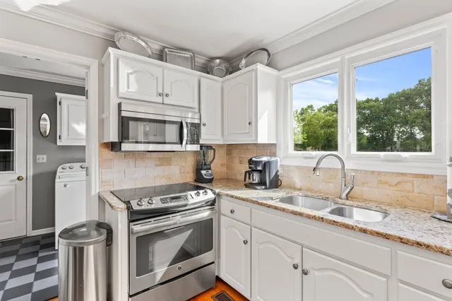 a kitchen with granite countertop a sink stainless steel appliances and cabinets