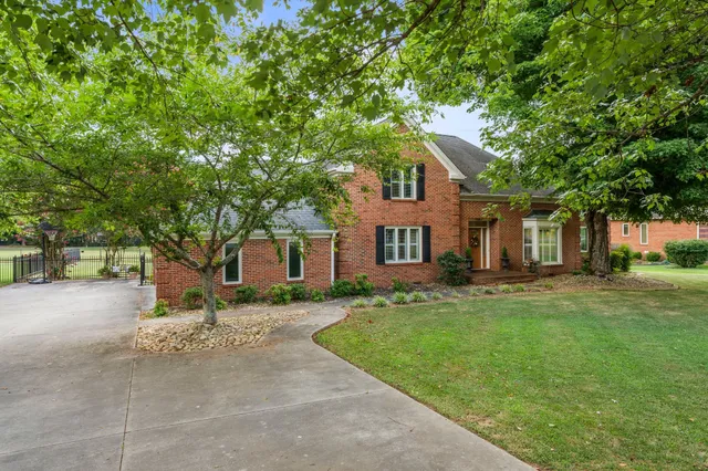 a front view of a house with a garden and trees